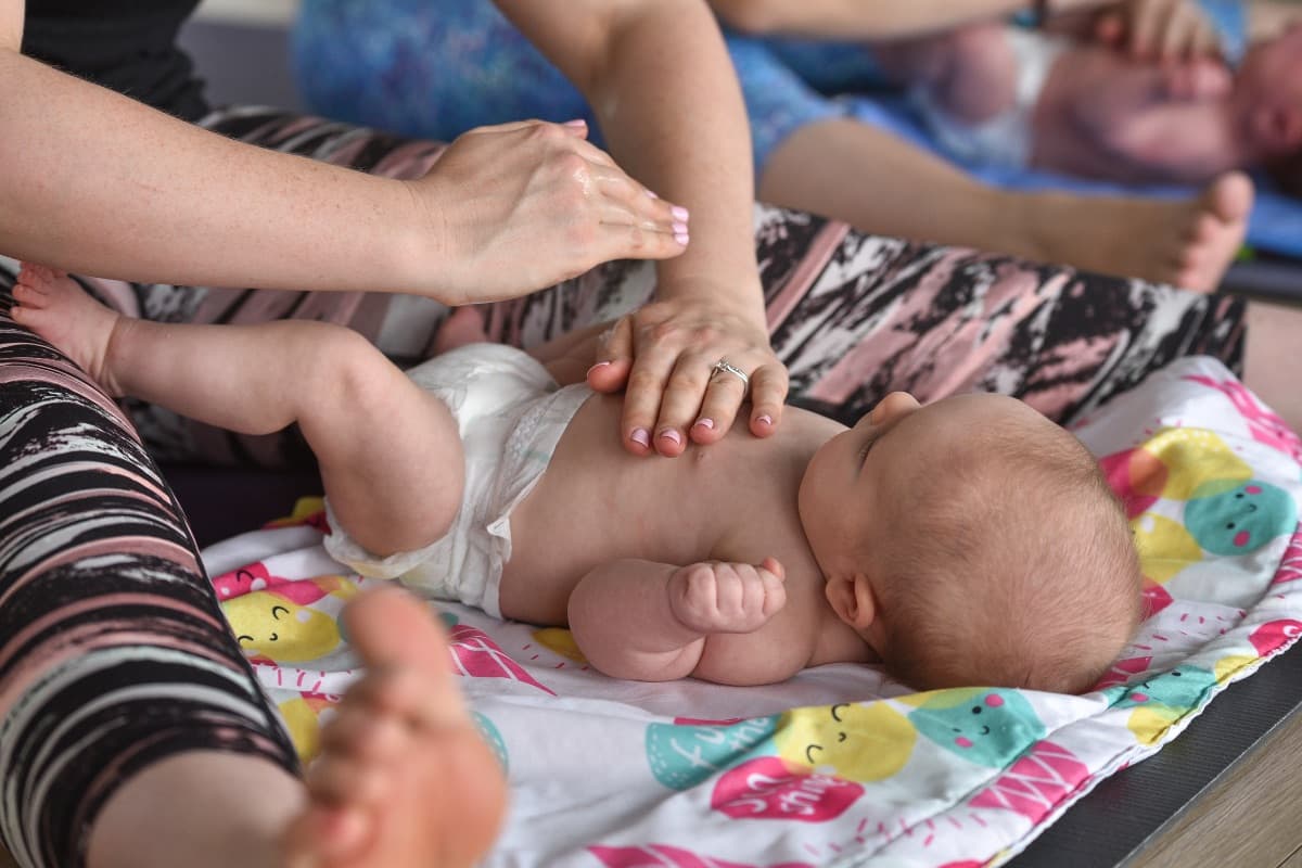 Parent gently massaging baby's tummy during a baby massage workshop