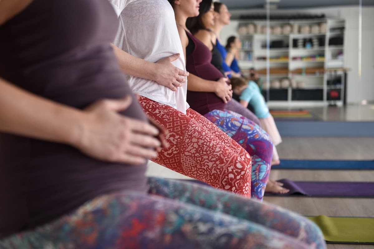 Pregnant women seated on mats cradling their bellies during a pregnancy class