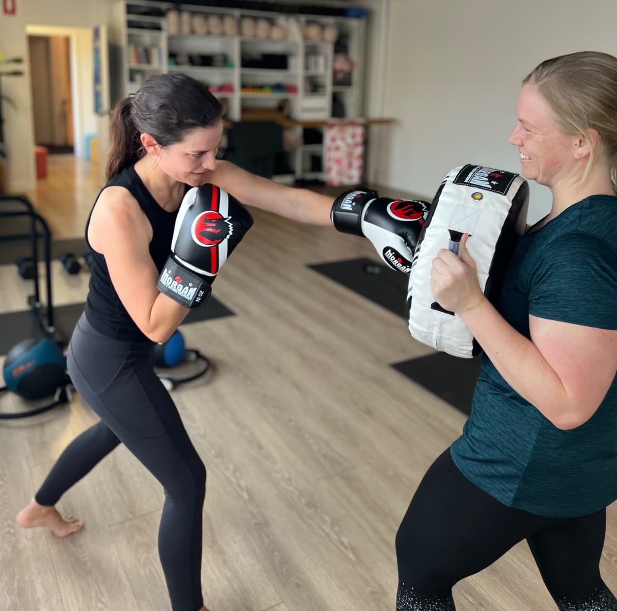 Two women doing pad work during a boxfit class at Evolvere Lane Cove