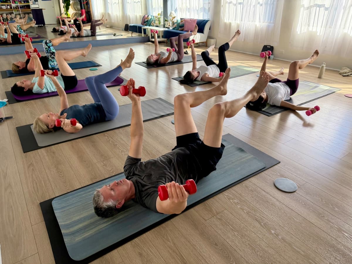 Pilates Sculpt class doing supine dumbbell exercises on mats at Evolvere Lane Cove